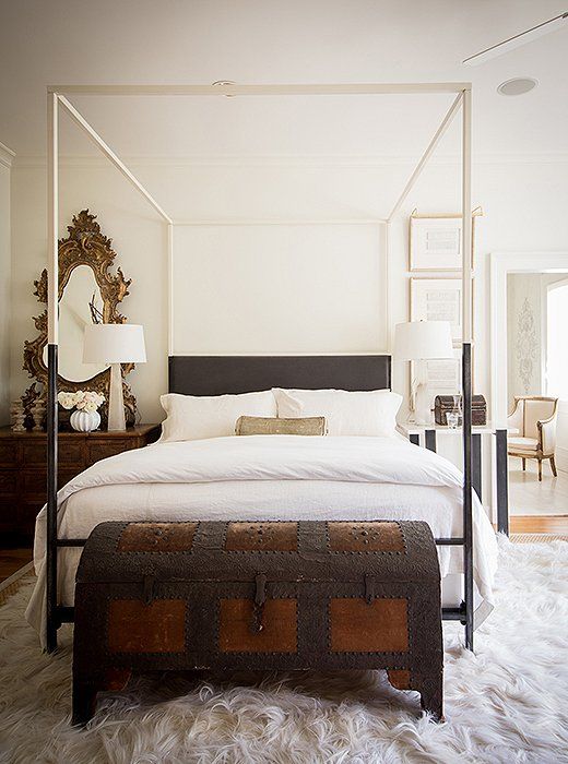 a large ironed vintage trunk as a storage piece and bench for a refined bedroom