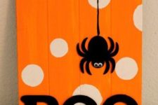 22 a bold orange and white polka dot sign with a spider applique and BOO letters