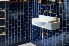 25 glossy navy tiles clad vertically for a bold art deco bathroom, chic brass touches