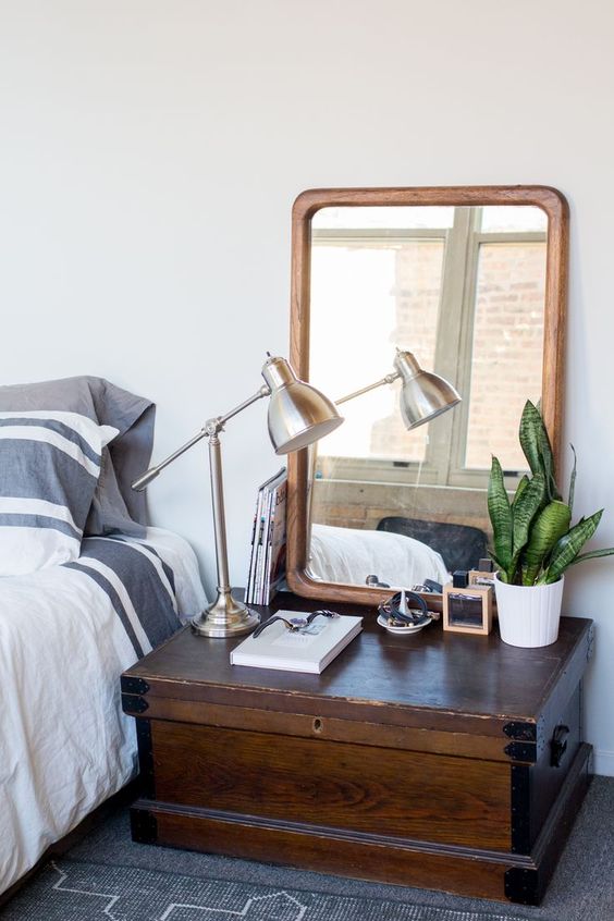 a wooden trunk used as a bedside table, detailing was removed to match the room decor