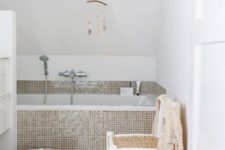 30 tiny glossy beige tiles civer the bathtub and the zone around it attracting attention