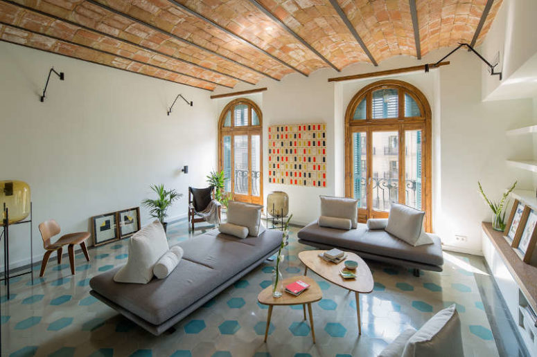 The living room kept the original windows and ceiling, modern comfy furniture and geo mosaic floors