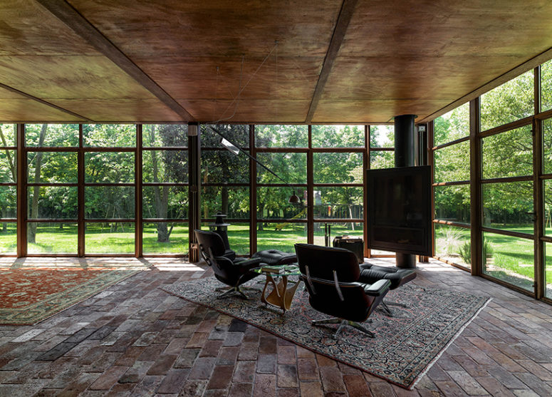 The glass volume totally feels like outside, here's a fireplace sitting space with loungers and a rug for comfort The glass volume totally feels like outside, here's a fireplace sitting space with loungers and a rug for comfort