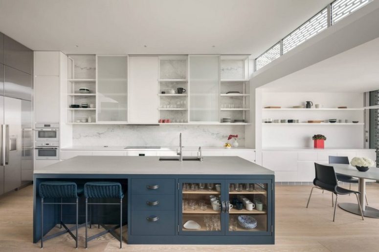 The kitchen is done in white and with a large navy and grey kitchen island and a marble backsplash