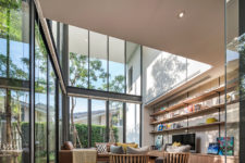 04 The living room features extensive glazing, a large shelving unit, a sitting space that seems to be outdoors due to the strong connection with it
