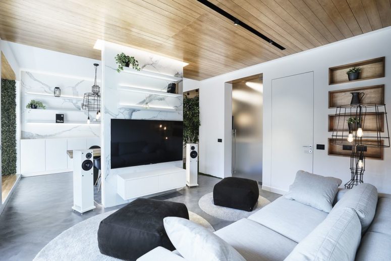 The living room is light-colored, light grey and white, with black touches and open shelving