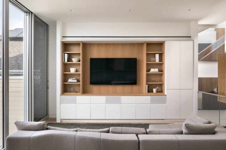 The living room is done with a sleek modern storage cabinet, a TV and a grey sofa