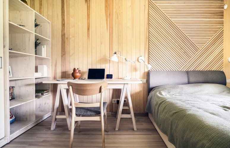 Upstairs there's a bedroom with a workspace and a shelving unit, everything here is clad with natural wood, too