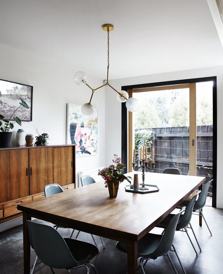 The dining zone is separated from the kitchen with large white cabinets, there's a large dining table and a mid-century sideboard