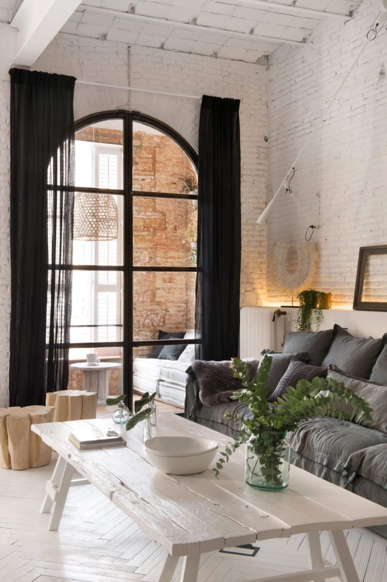 The living room is done with grey furniture, whitewashed tables, and the windows lead to a sunroom