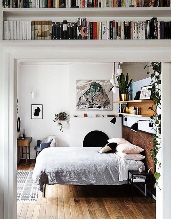 The bedroom is done with a non-working fireplace, a bed with a leather headboard, some artworks of the owner and a shelving unit over the bed