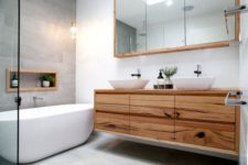 07 a modern space with a grey tile wall, a wooden vanity and white sinks and a bathtub