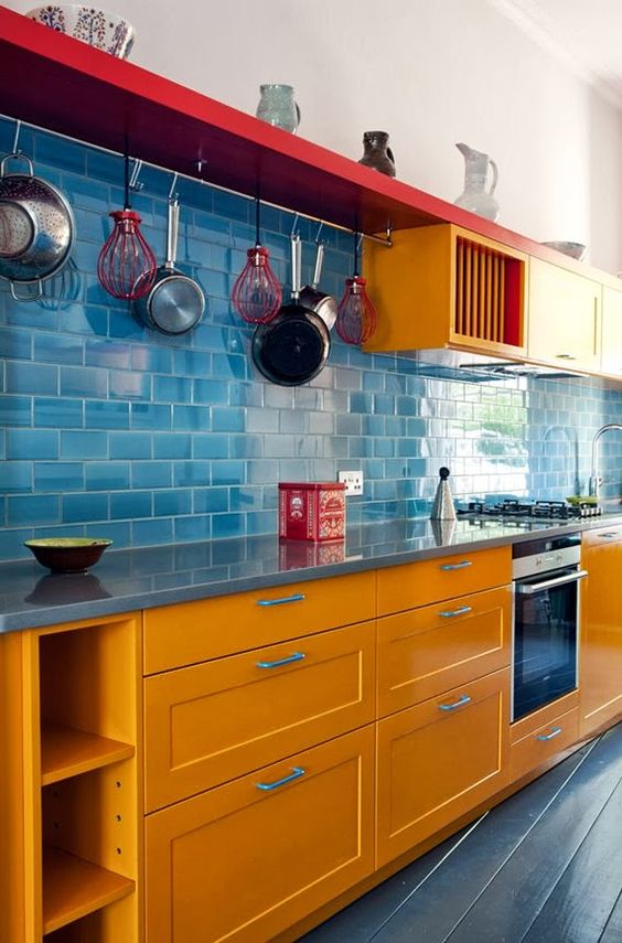 orange cabinets, a blue tile backsplash and floors and a red shelf for a colorful space