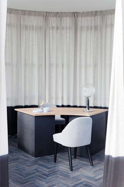 The home office features black furniture and light-colored tabletops and quirky lamps