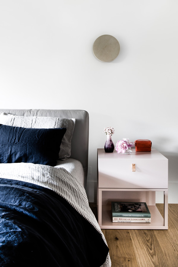 The master bedroom is done with an upholstered bed, blush nightstands