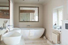 11 a modern soft-colored bathroom with a free-standing tub, white sinks and neutral tiles