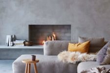 11 a modern space with concrete walls, a working fireplace, comfy upholstered sofa and textiles
