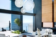 13 a gorgeous indoor-outdoor living room with unique lamps, a wood panel wall with a fireplace and white furniture