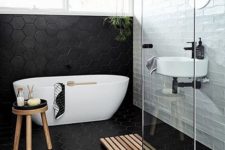13 a modern space with subway tiles, black geo tiles, a free-standing bathtub, some wooden touches
