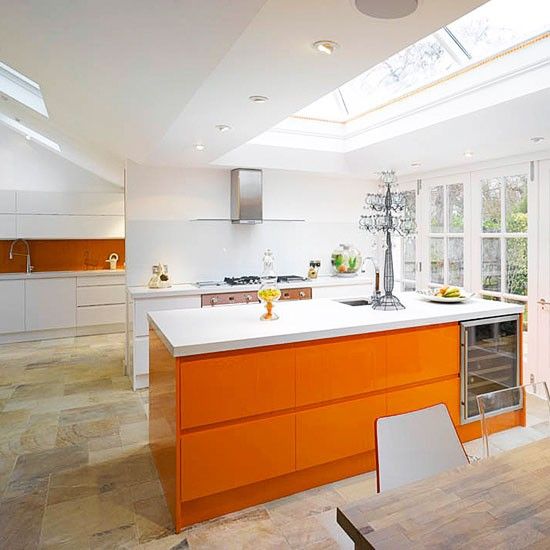 an airy all white kitchen with a bold orange kitchen island and a burnt orange backsplash