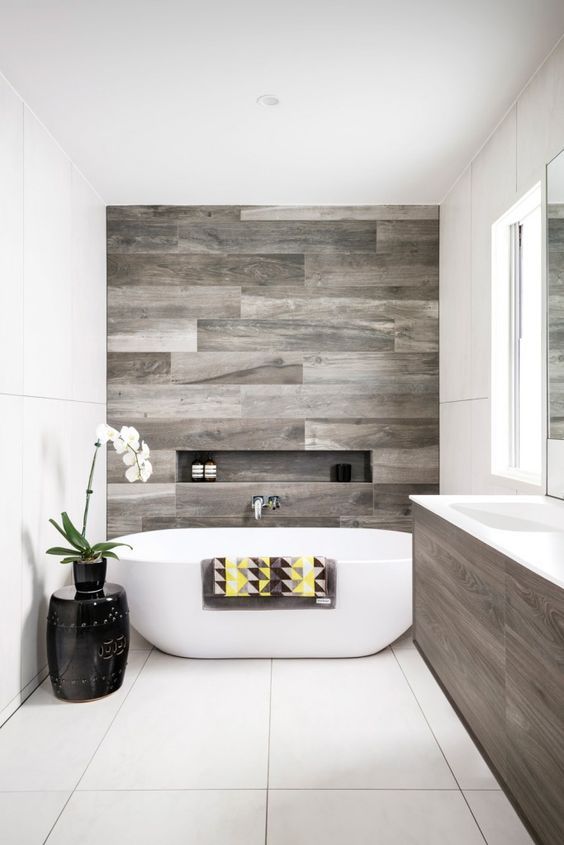 a modern bathroom with a reclaimed wood wall and vanity, a free-standing tub and a side table with an orchid