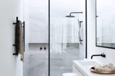 18 a modern space with grey marble tiles, white cabinets, black frame glass door and faucets