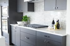 19 a dark grey kitchen with a light tile backsplash and white counters looks edgy and chic