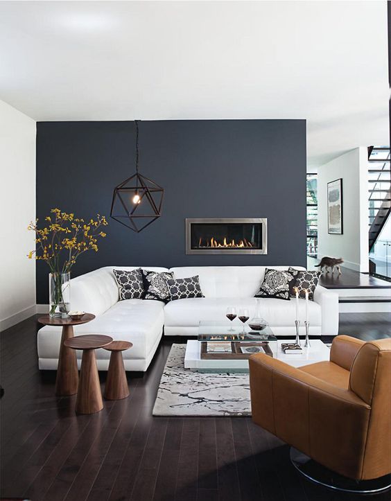 monochrome with a black statement wall, white furniture, wooden tables and an amber chair