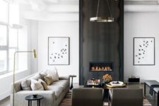 20 a black and white space with an accent dark fireplace wall, an industrial chandelier and comfy modern furniture