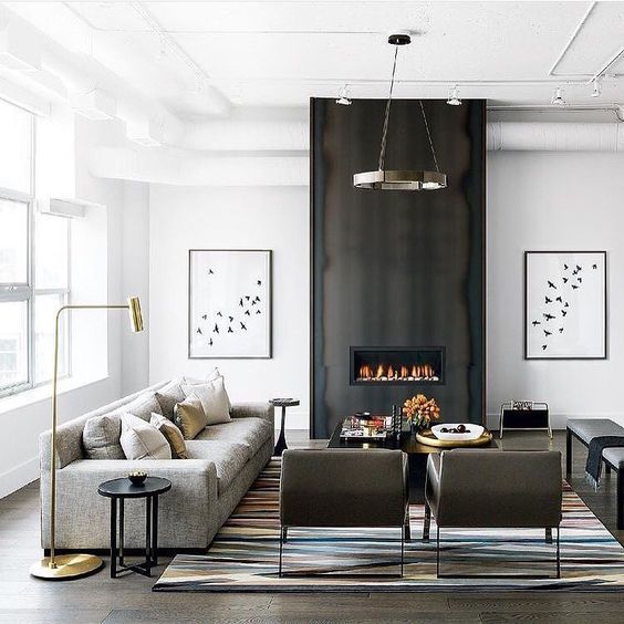 a black and white space with an accent dark fireplace wall, an industrial chandelier and comfy modern furniture