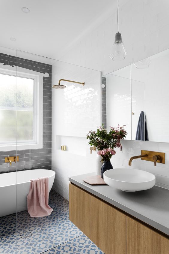 a modern space with mosaic tiles, grey subway tiles, a wood and concrete vanity and metallic fixtures