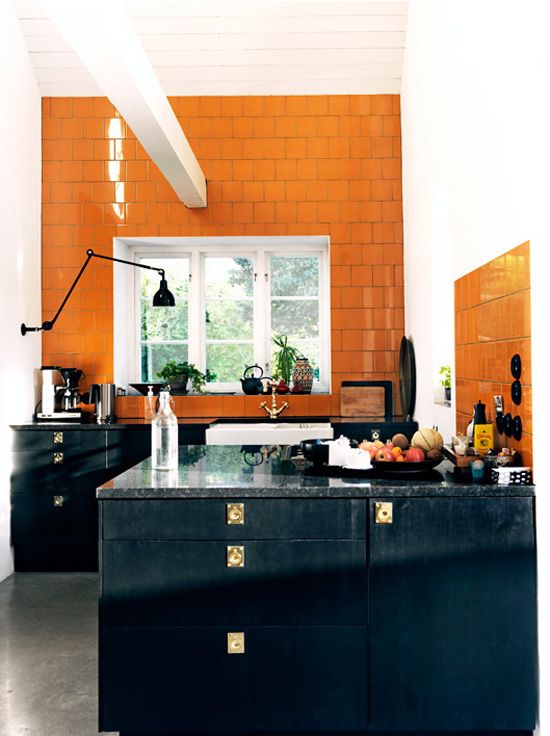 a vintage black kitchen with a bold orange tile backsplash extended above for a bold contrast