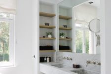 21 a functional sink space with white marble, wooden shelves and a large mirror
