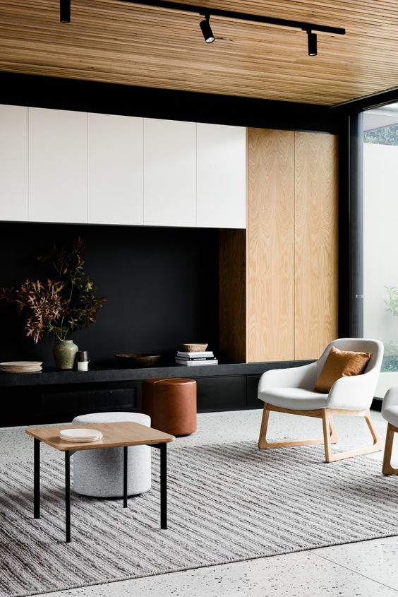 a modern living room with light-colored wood panels, black and white and laconic furniture