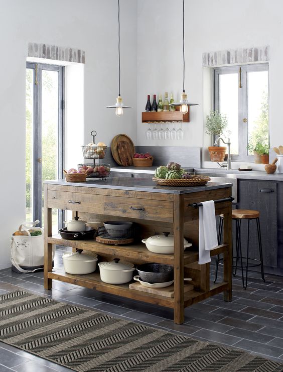 a reclaimed wood kitchen island contrasts with the dark furniture and tiles around