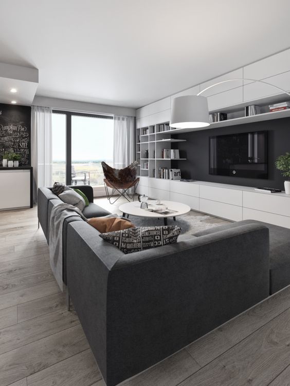 a monochrome black and white living room with a large setional sofa and a wall storage unit