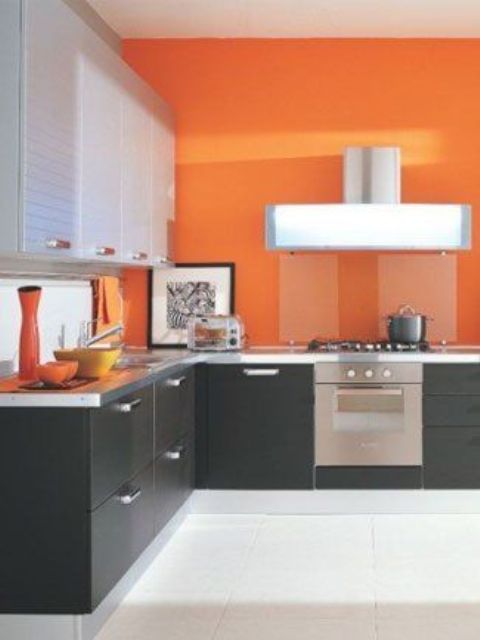 an ultra-modern kitchen with black and seehr cabinets and sleek bold orange walls
