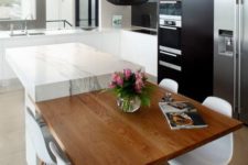 24 a black kitchen with a white marble kitchen island and an additional tabletop for having meals