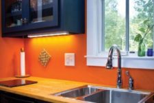 26 modern navy cabinets are accentuated with an orange backsplash and neutral wood countertops