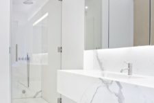 27 a modern marble bathroom with a seamless shower, a large mirror and a marble vanity
