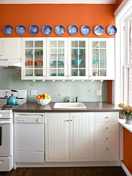 neutral kitchen cabinets stand out in orange walls and bold blue plates