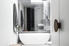 29 a modern white space with a free-standing tub, white fixtures and a wooden stool