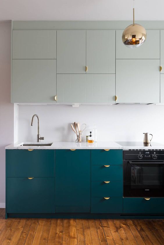 a teal and mint modern kitchen with a white backsplash and copper touches looks bold and chic