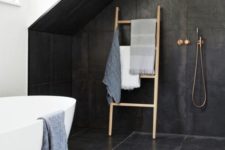 31 attic bathroom with attic accentuated with black tiles and some brass fixtures