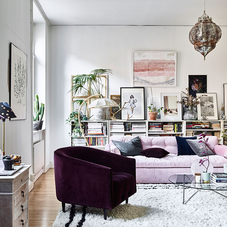 A Moroccan-styled lamp, a pink velvet sofa, an aubergine-colored velvet armchair make up a bold and cool space, and vintage finds and lots of books and artworks look cool