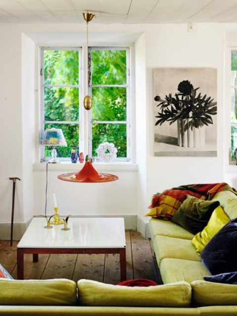 A lemon yellow corner sofa and colorful lamps and pillows create a cool and bold boho space, which raises the mood