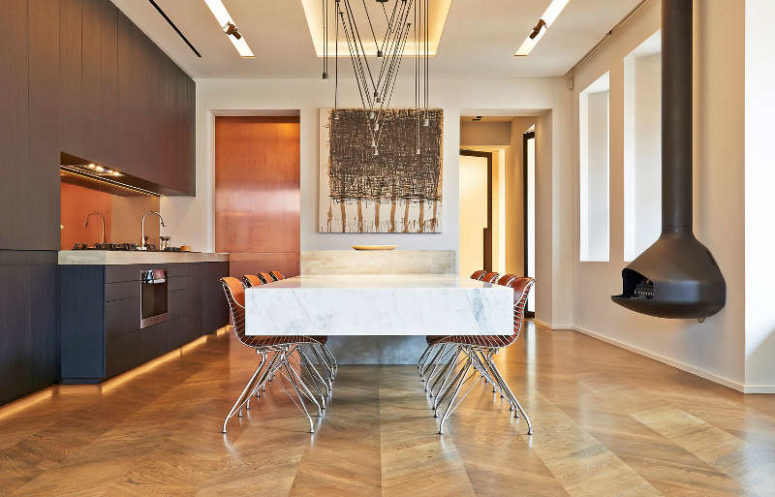 There's a hearth, a metallic artwork, hanging lamps and a breakfast zone with a marble tabletop and additional lights