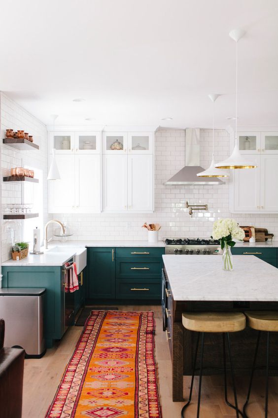 a chic kitchen with dark green and white cabinets, a white suwaby tile backsplash and open shelving
