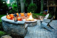 02 a gorgeous firepit zone with a round stone bench, candle lanterns and orange pillows for a fall feel