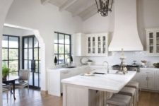 02 a white vintage farmhouse kitchen with a large hood, vintage lamps and a chic kitchen island